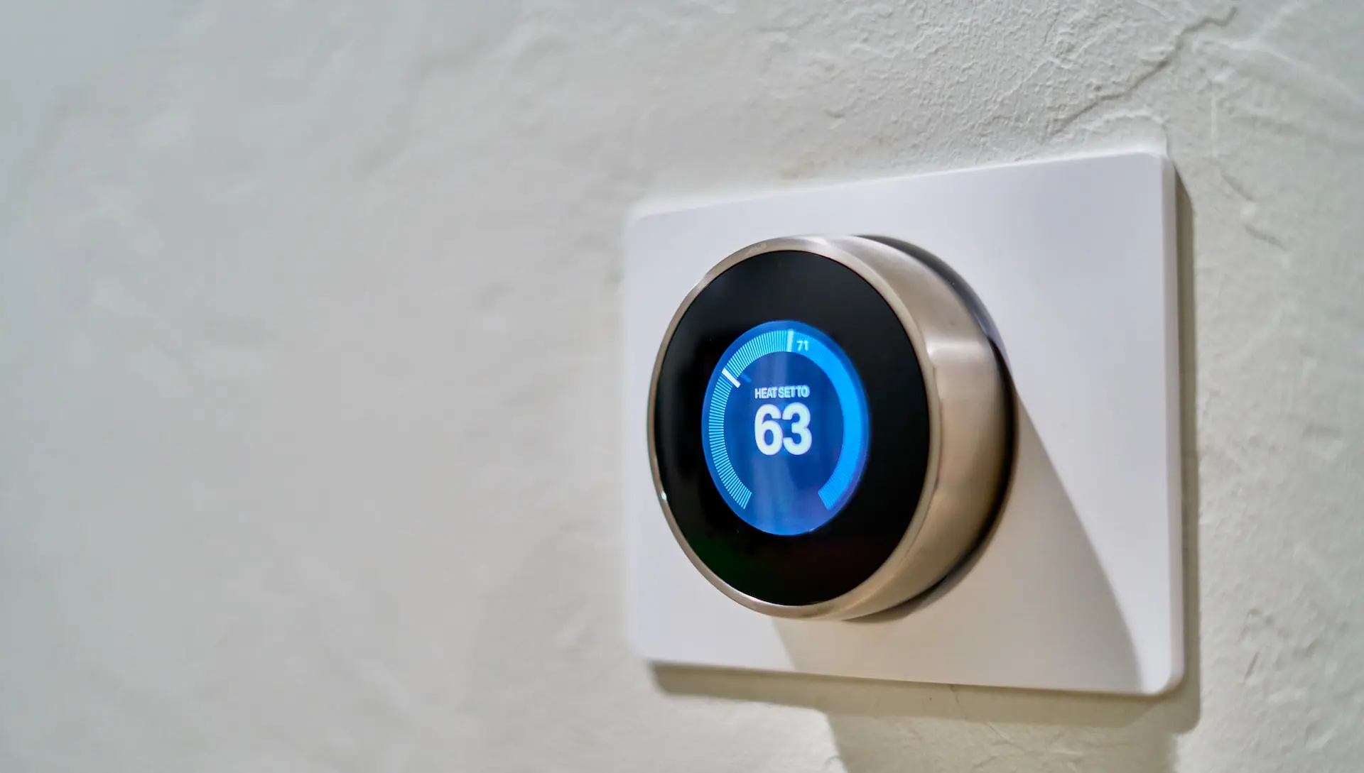 gray Nest thermostat displaying at 63